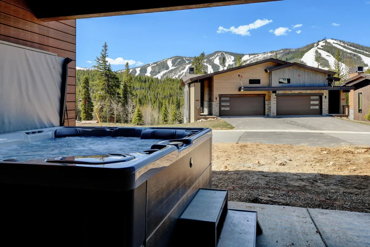 An inviting exterior shot of a modern hot tub perched on a deck, overlooking expansive mountain views. The villa’s architecture and serene setting are highlighted, suggesting luxury, relaxation, and the possibility of stargazing or wildlife spotting from the comfort of your own outdoor retreat.